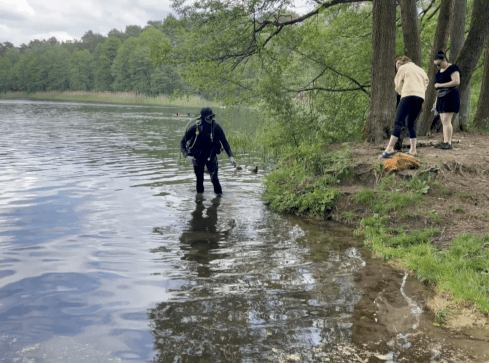 Dwie kiełbasy, puszki i butelki oraz przynęty wędkarskie. Sprzątan - grafika